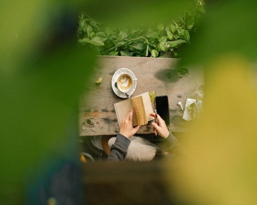 person reading a physical book during a coffee break outdoors